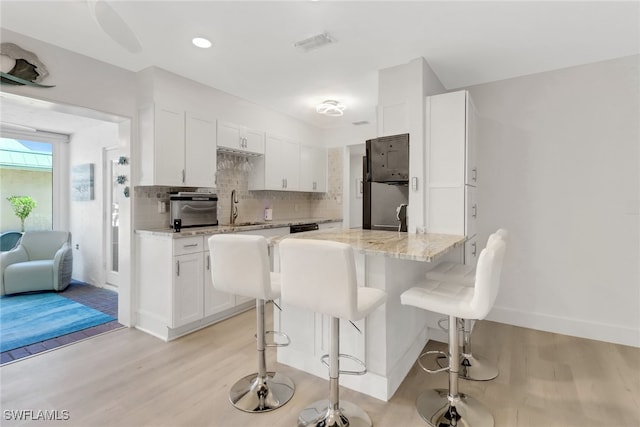 3905 Del Prado Blvd S Unit D-101, Cape Coral, FL 33904 - kitchen with a sink, white cabinetry, light wood-style floors, light stone counters, and recessed lighting