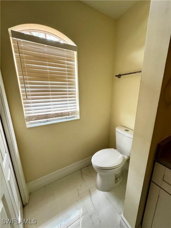 25560 Springtide Ct, Bonita Springs, FL 34135 - half bathroom featuring marble finish flooring, toilet, and baseboards