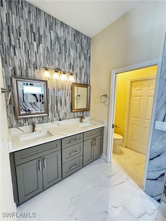 25560 Springtide Ct, Bonita Springs, FL 34135 - bathroom featuring an accent wall, toilet, marble finish flooring, double vanity, and baseboards