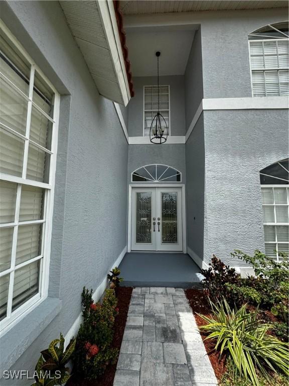 25560 Springtide Ct, Bonita Springs, FL 34135 - view of exterior entry featuring stucco siding and french doors