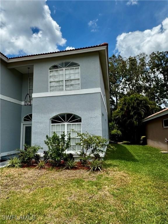 25560 Springtide Ct, Bonita Springs, FL 34135 - view of side of home with a lawn and stucco siding