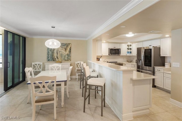 6672 Estero Blvd Unit A207, Fort Myers Beach, FL 33931 - kitchen featuring stainless steel appliances, ornamental molding, glass insert cabinets, white cabinetry, and a peninsula