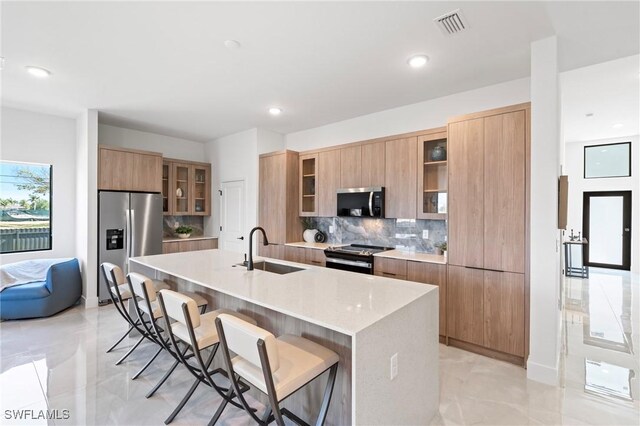 1917 NW 24th Ave, Cape Coral, FL 33993 - kitchen featuring appliances with stainless steel finishes, modern cabinets, a sink, tasteful backsplash, and a kitchen breakfast bar