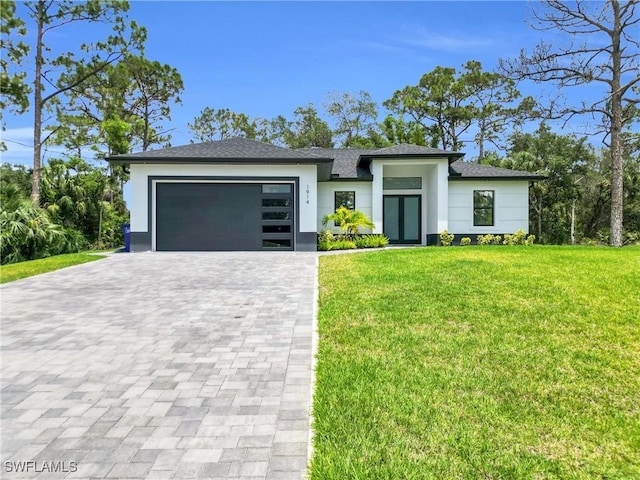 1914 Sunniland Blvd, Lehigh Acres, FL 33971 - prairie-style house with decorative driveway, a front lawn, an attached garage, stucco siding, and french doors