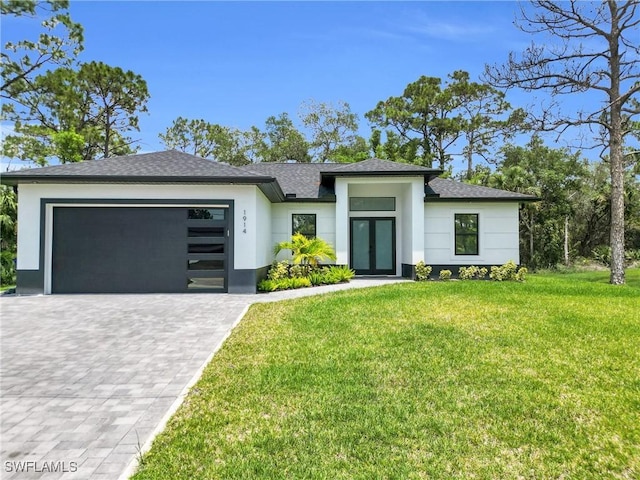 1914 Sunniland Blvd, Lehigh Acres, FL 33971 - view of front of house with an attached garage, decorative driveway, french doors, stucco siding, and a front lawn