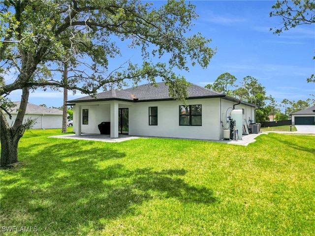1914 Sunniland Blvd, Lehigh Acres, FL 33971 - back of property with stucco siding, a lawn, a patio area, and central AC