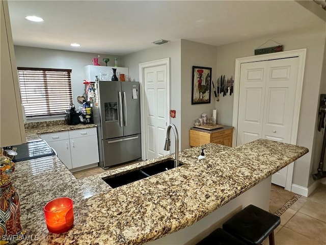 352 Paisley Ave, Lehigh Acres, FL 33974 - kitchen with stainless steel fridge, light stone counters, light tile patterned floors, recessed lighting, and white cabinets