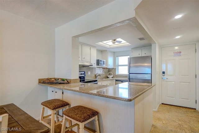 5000 Estero Blvd Unit 202, Fort Myers Beach, FL 33931 - kitchen featuring appliances with stainless steel finishes, under cabinet range hood, a sink, a peninsula, and backsplash