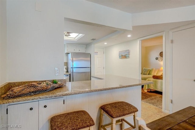 5000 Estero Blvd Unit 202, Fort Myers Beach, FL 33931 - kitchen with freestanding refrigerator, a breakfast bar, light carpet, recessed lighting, and a peninsula