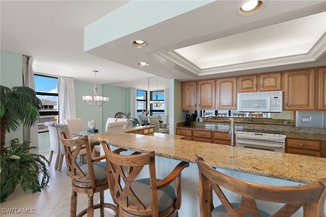 300 S Collier Blvd Unit 2304, Marco Island, FL 34145 - kitchen featuring white appliances, a chandelier, a breakfast bar area, light stone counters, and light tile patterned floors