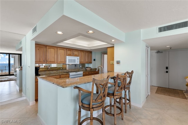 300 S Collier Blvd Unit 2304, Marco Island, FL 34145 - kitchen with white appliances, light stone counters, a peninsula, light tile patterned floors, and a breakfast bar area