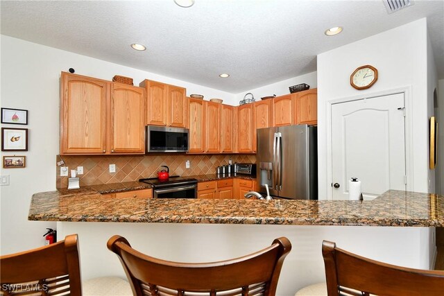 2842 Via Piazza Loop, Fort Myers, FL 33905 - kitchen with stainless steel appliances, tasteful backsplash, a breakfast bar, a peninsula, and a sink