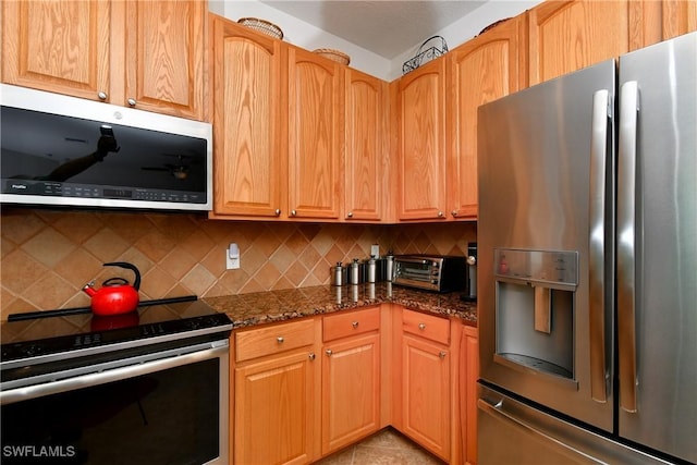 2842 Via Piazza Loop, Fort Myers, FL 33905 - kitchen featuring appliances with stainless steel finishes, decorative backsplash, dark stone counters, and light tile patterned floors
