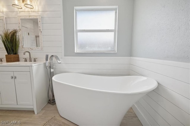 5748 Linden Ln, Bokeelia, FL 33922 - bathroom with vanity, a soaking tub, wainscoting, and wood finished floors