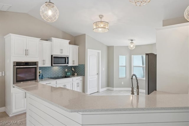 5748 Linden Ln, Bokeelia, FL 33922 - kitchen with stainless steel appliances, lofted ceiling, decorative backsplash, white cabinetry, and light stone countertops