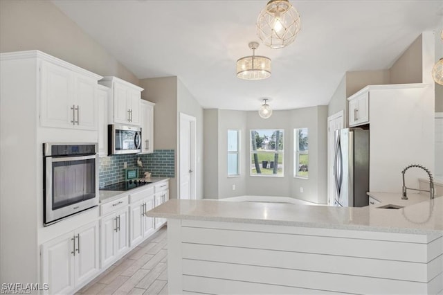 5748 Linden Ln, Bokeelia, FL 33922 - kitchen featuring stainless steel appliances, a sink, tasteful backsplash, white cabinetry, and light stone counters
