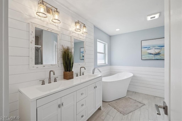 5748 Linden Ln, Bokeelia, FL 33922 - bathroom featuring double vanity, a soaking tub, a wainscoted wall, and a shower