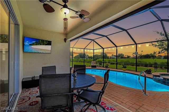 3147 Walnut Grove Ln, Alva, FL 33920 - pool at dusk featuring a patio area, a pool with connected hot tub, ceiling fan, and glass enclosure