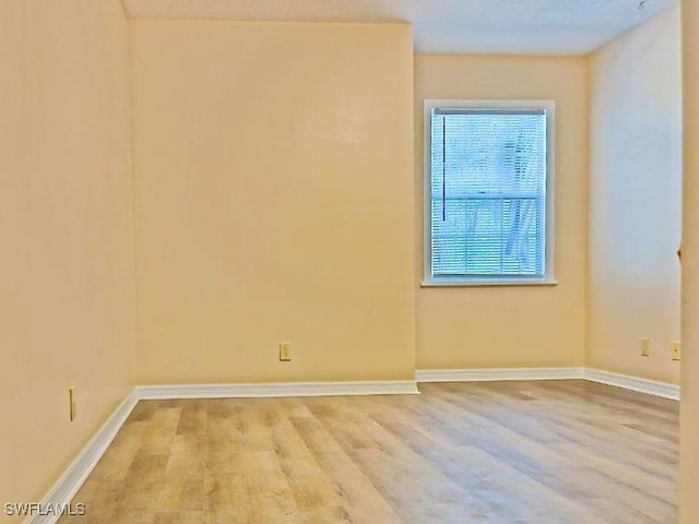 spare room featuring wood finished floors and baseboards