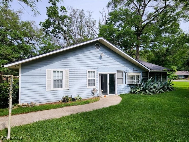 rear view of property featuring a lawn and a sunroom