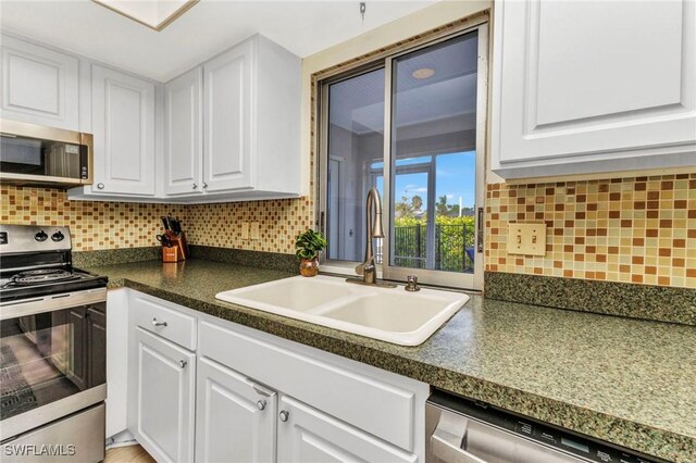 125 Donna Ct, Punta Gorda, FL 33950 - kitchen featuring stainless steel appliances, a sink, white cabinets, dark countertops, and tasteful backsplash