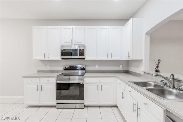 14183 Fall Creek Ct, Naples, FL 34114 - kitchen with stainless steel appliances, a sink, light tile patterned floors, white cabinetry, and light countertops