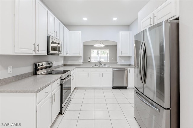 14183 Fall Creek Ct, Naples, FL 34114 - kitchen with appliances with stainless steel finishes, light countertops, arched walkways, white cabinets, and a sink