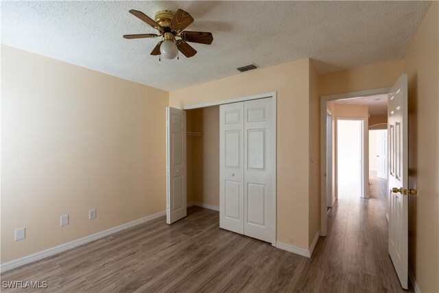 2022 Hunters Trace Cir, Middleburg, FL 32068 - unfurnished bedroom featuring wood finished floors, baseboards, a closet, a textured ceiling, and ceiling fan