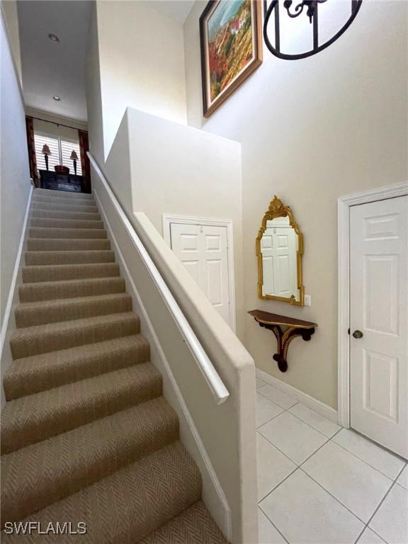 650 Vintage Reserve Cir Unit 5C, Naples, FL 34119 - staircase with tile patterned flooring, baseboards, and a towering ceiling