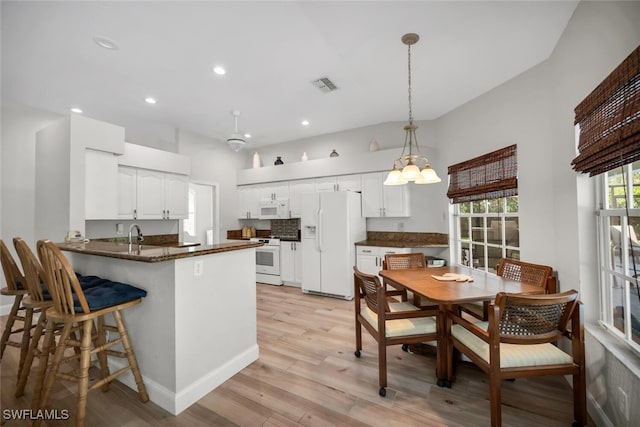 28996 Seton Ct, Bonita Springs, FL 34134 - kitchen with white appliances, a peninsula, light wood-type flooring, white cabinets, and a kitchen breakfast bar