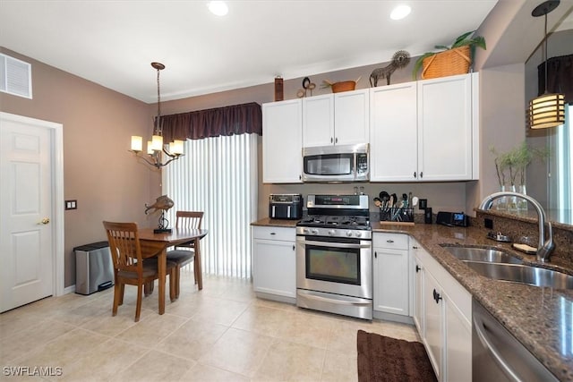 9327 Trieste Dr, Fort Myers, FL 33913 - kitchen with appliances with stainless steel finishes, a sink, a chandelier, dark stone countertops, and white cabinetry