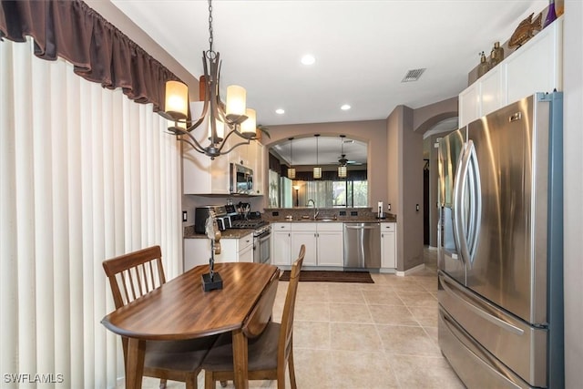 9327 Trieste Dr, Fort Myers, FL 33913 - kitchen with stainless steel appliances, a sink, a chandelier, white cabinets, and light tile patterned flooring