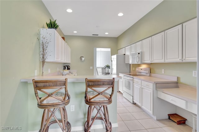 10020 Sky View Way Unit 905, Fort Myers, FL 33913 - kitchen featuring white appliances, a kitchen breakfast bar, white cabinets, and recessed lighting
