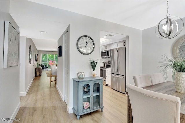 773 Wiggins Lake Dr Unit 101, Naples, FL 34110 - corridor with a chandelier, light wood-type flooring, and baseboards