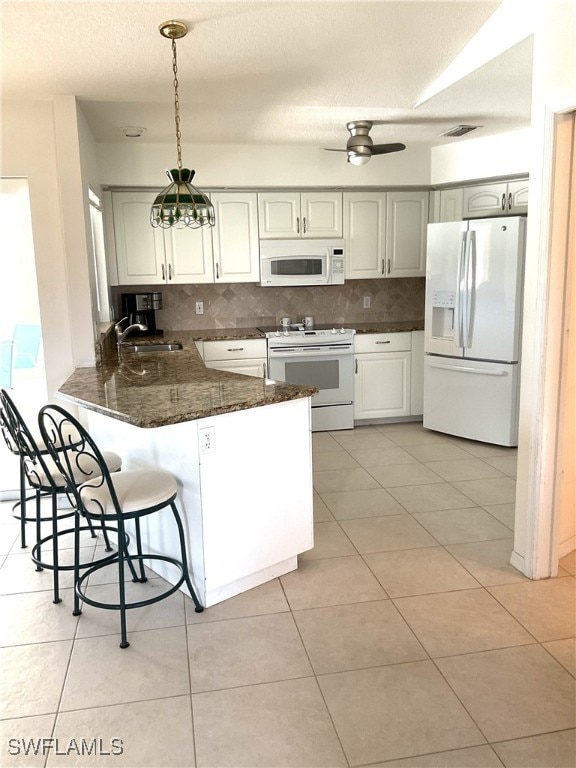 86 Pinehurst Pl, Rotonda West, FL 33947 - kitchen with white appliances, a sink, a peninsula, decorative backsplash, and a breakfast bar