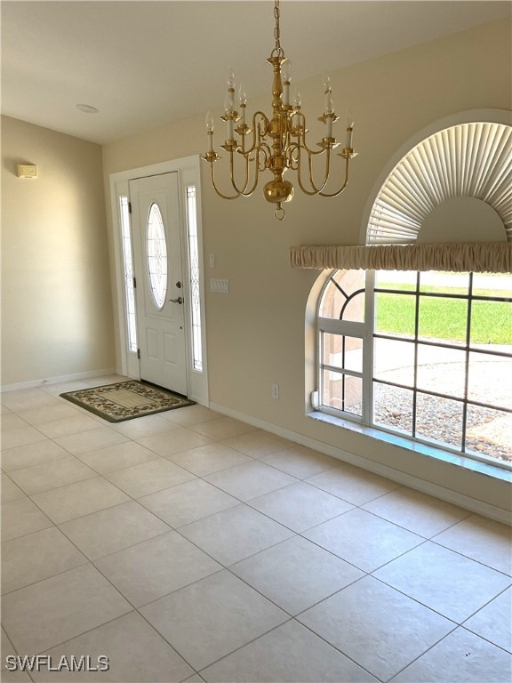 86 Pinehurst Pl, Rotonda West, FL 33947 - foyer entrance featuring plenty of natural light, baseboards, light tile patterned floors, and a chandelier