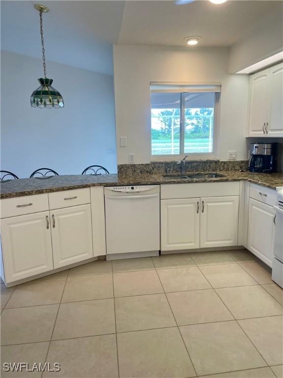 86 Pinehurst Pl, Rotonda West, FL 33947 - kitchen with white appliances, white cabinetry, dark stone counters, light tile patterned floors, and pendant lighting