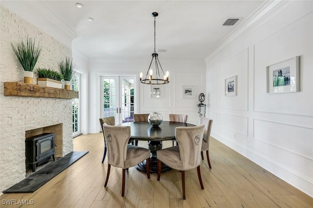 1550 Gordon Dr, Naples, FL 34102 - dining room featuring a decorative wall, crown molding, a chandelier, a wood stove, and light wood-style flooring