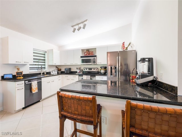 725 Grove Dr, Naples, FL 34120 - kitchen featuring stainless steel appliances, vaulted ceiling, a peninsula, a breakfast bar, and white cabinets