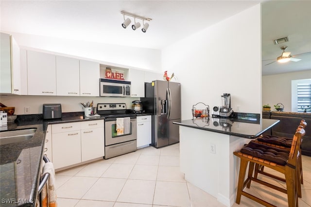 725 Grove Dr, Naples, FL 34120 - kitchen featuring appliances with stainless steel finishes, lofted ceiling, a kitchen bar, white cabinetry, and light tile patterned flooring
