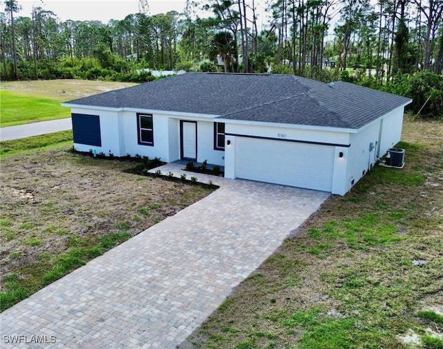 ranch-style house featuring an attached garage, stucco siding, roof with shingles, and decorative driveway