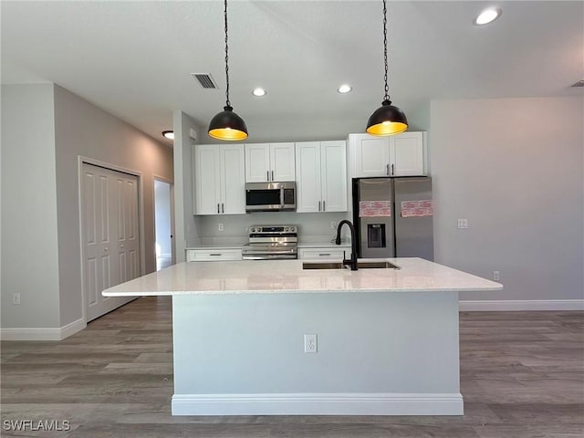 kitchen with appliances with stainless steel finishes, a sink, baseboards, a center island with sink, and recessed lighting