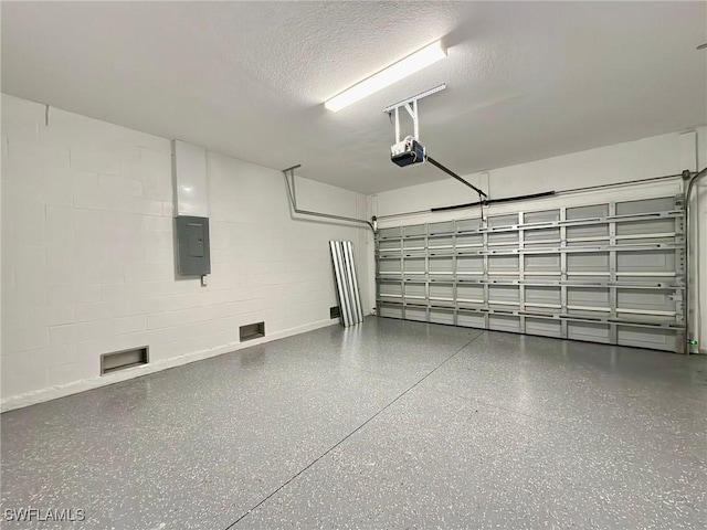 garage with electric panel, a garage door opener, and concrete block wall