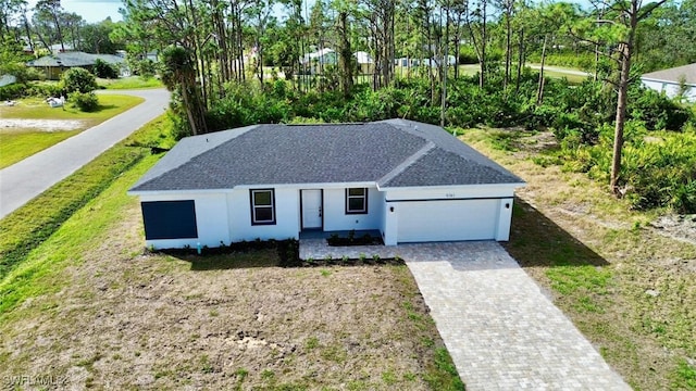 ranch-style home with a garage, stucco siding, roof with shingles, and decorative driveway