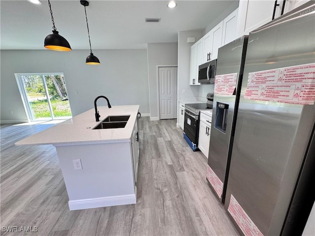 kitchen with appliances with stainless steel finishes, a sink, light wood-style floors, a kitchen island with sink, and white cabinetry