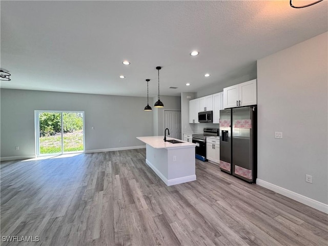 kitchen featuring stainless steel appliances, open floor plan, light wood-style flooring, baseboards, and recessed lighting