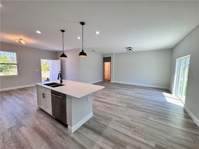 kitchen featuring dishwasher, a sink, open floor plan, recessed lighting, and baseboards