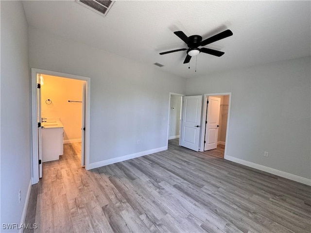 unfurnished bedroom featuring a walk in closet, wood finished floors, baseboards, and a closet
