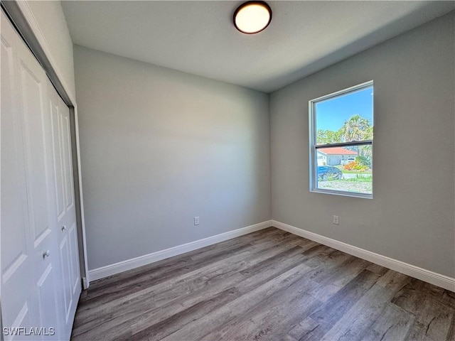 unfurnished bedroom with a closet, wood finished floors, and baseboards