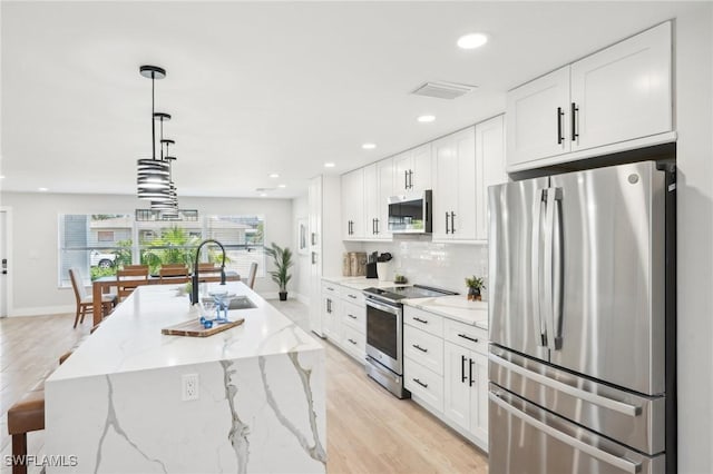 18195 Cutlass Dr, Fort Myers Beach, FL 33931 - kitchen with appliances with stainless steel finishes, white cabinetry, a sink, light wood-style flooring, and recessed lighting